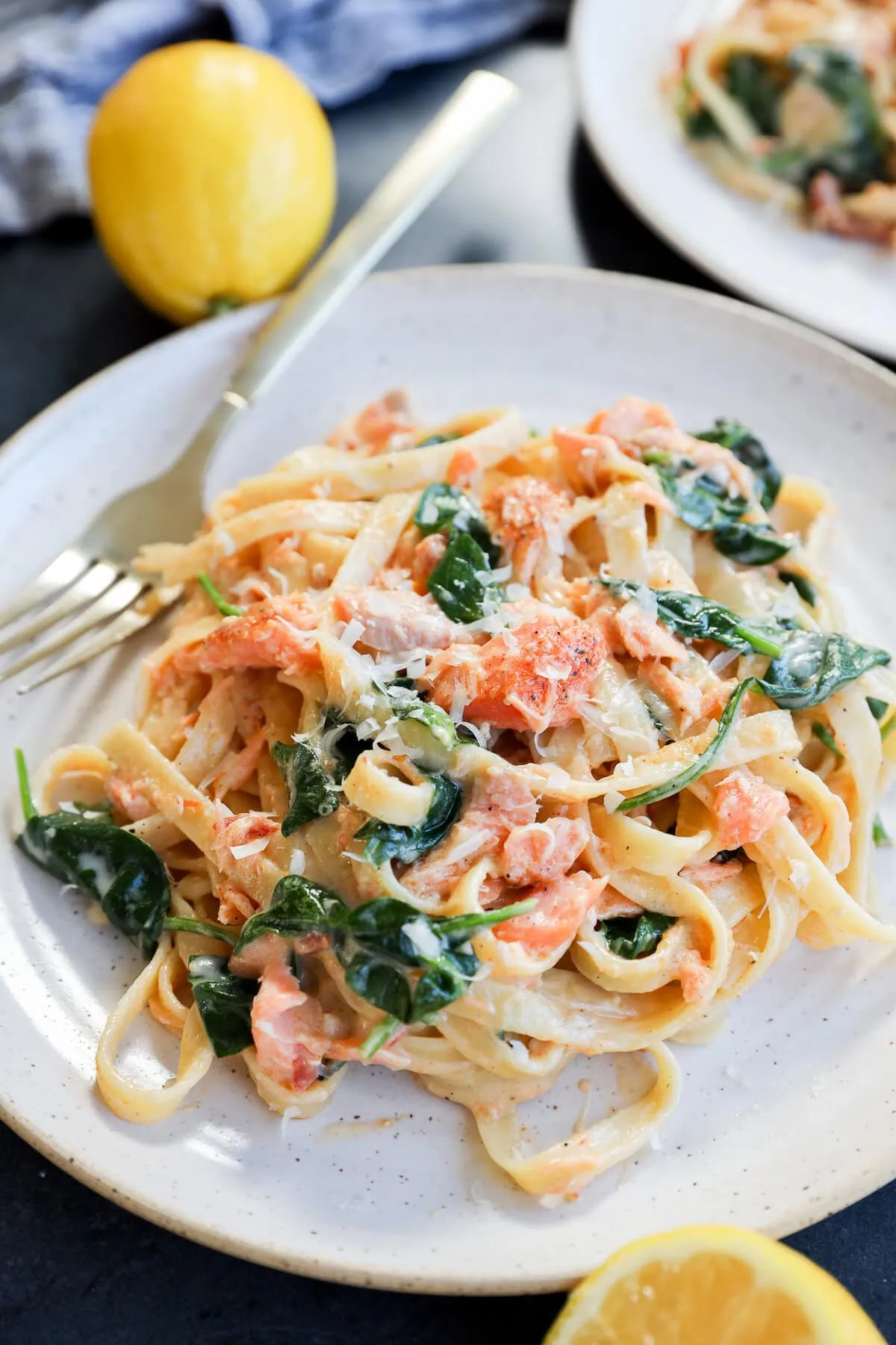 easy creamy fettuccine with seafood and greens on a plate with lemons and a fork