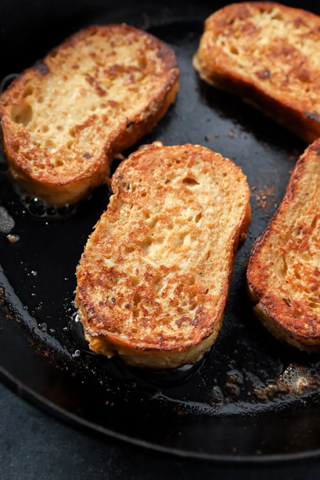 frying sourdough french toast slices in a cast iron skillet