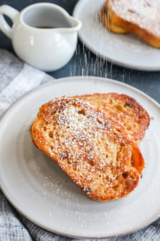 sprinkling powdered sugar on slices of french toast